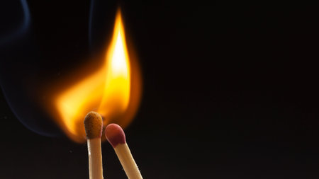 Burning wooden match with a red match head on a black background. Close upの写真素材