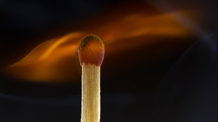 Burning wooden match with a red match head on a black background. Close upの写真素材