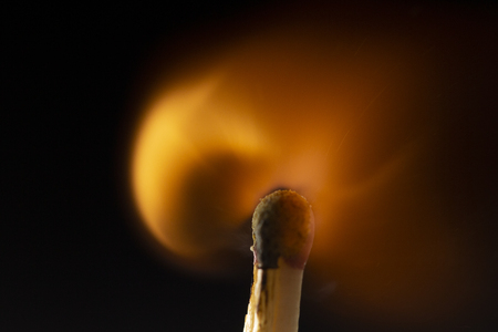Burning wooden match with a red match head on a black background. Close upの写真素材
