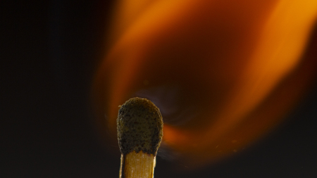 Burning wooden match with a red match head on a black background. Close upの写真素材