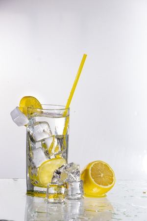 A glass of lemonade on a light background with splashing water close upの写真素材