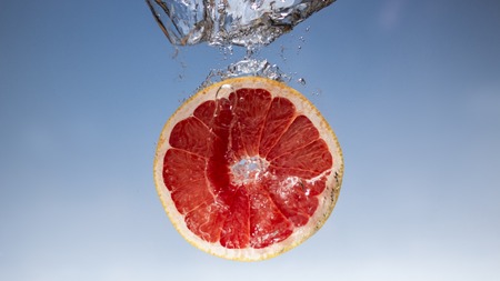 Fresh grapefruit with water splash on blue backgroundの写真素材