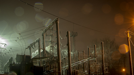 Power transmission towers and their silhouettes against the background of the night sky in the industrial urban area. Illuminated by spotlightsの写真素材