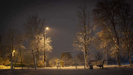 Beautiful rural winter snow-covered street with lanterns on. And light trails from cars Backgroundの写真素材