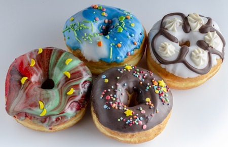 Fresh colorful donuts topped with glaze and decorated with colorful decorations on a white background Cose upの写真素材