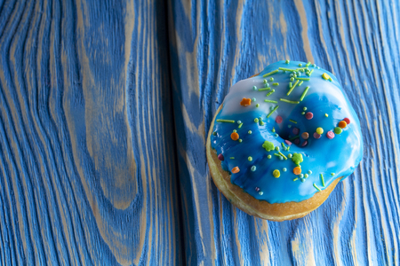 Blue donut on the old blue wooden table, with a clearly visible wood texture close upの写真素材