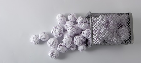 A trashcan full of crumpled paper on white backgroundの写真素材