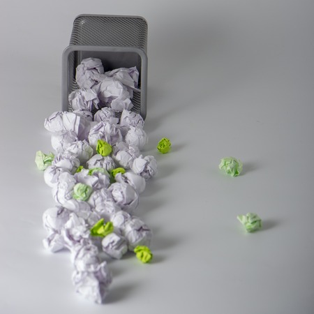A trashcan full of crumpled paper on white backgroundの写真素材