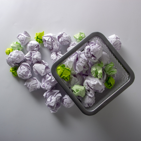 A trashcan full of crumpled paper on white backgroundの写真素材