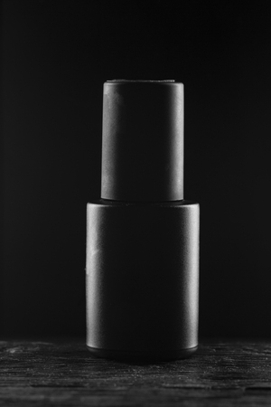 Black gel nail polish in a black tube on a black background close upの写真素材