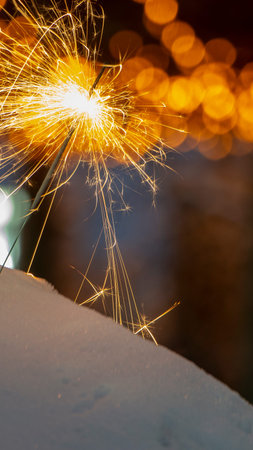 burning sparkler on bokeh background from lights of garland close up