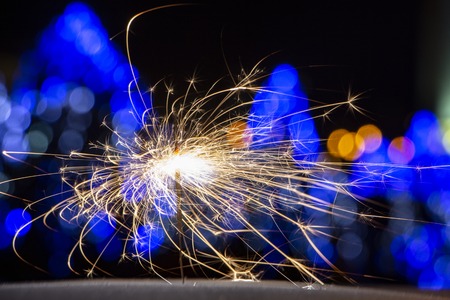 burning sparkler on bokeh background from lights of garland close upの写真素材