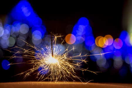 burning sparkler on bokeh background from lights of garland close upの写真素材