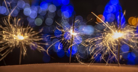 burning sparkler on bokeh background from lights of garland close upの写真素材