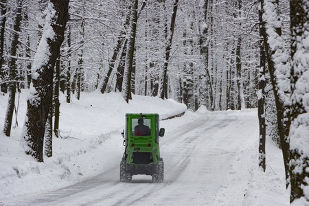 snow machine, green tractor cleans the snow from the snow in the background of the forestの写真素材