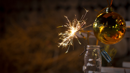 Rustic wooden wall with a sparkler and golden bokeh Christmas concept close upの写真素材