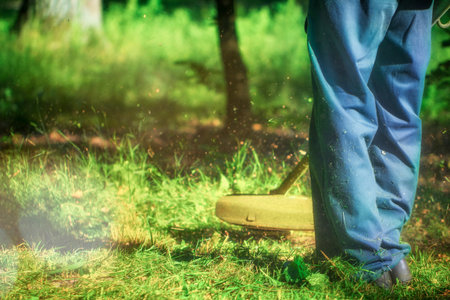 The gardener mows weeds. small parts of vegetation scatter in different directions close up