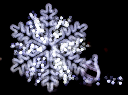 Christmas background, bokeh in the shape of a snowflake, on a black backgroundの写真素材