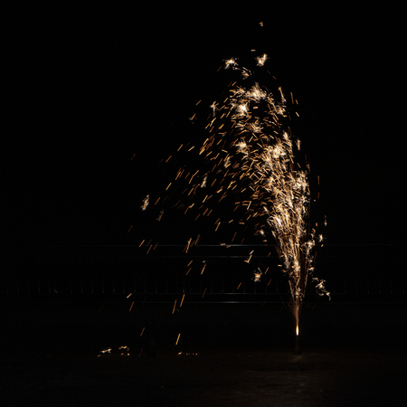 Yellow orange firework against night sky close up backgroundの写真素材