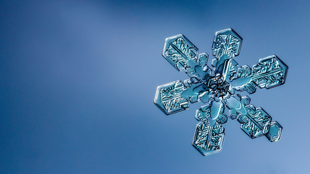 Beautiful snow flake on light blue background close-upの写真素材