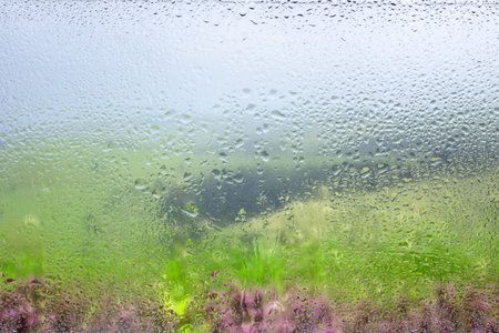 Water droplets on a window pane with beautiful defocused scenery outside. Background