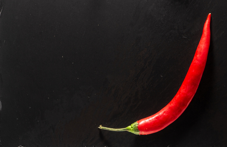 Red hot chili peppers on a black slate background texture close-upの写真素材