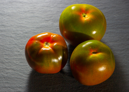 Fresh red tomatoes on dark stone table or black background. close upの写真素材