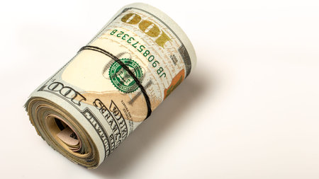 100 dollar bills twisted into tube and tied with an elastic band. white background. Close up