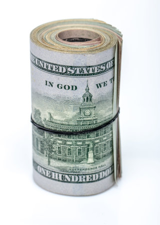100 dollar bills twisted into tube and tied with an elastic band. white background. Close up