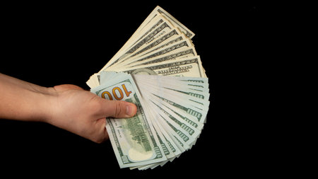 Fan of dollars in a male's hand on a black background, close up