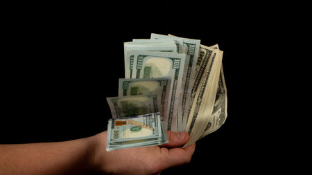 Fan of dollars in a male's hand on a black background, close up
