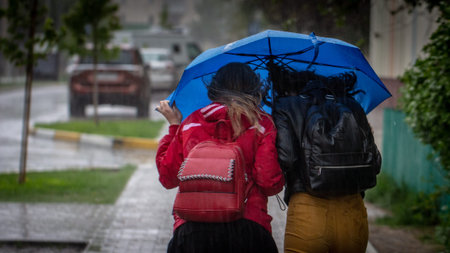 People hide from rain under umbrellas in a rainy day on the street of the city