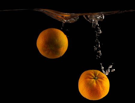 Mandarin falls into the water on a black background close upの写真素材