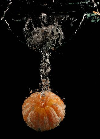 Mandarin falls into the water on a black background close upの写真素材