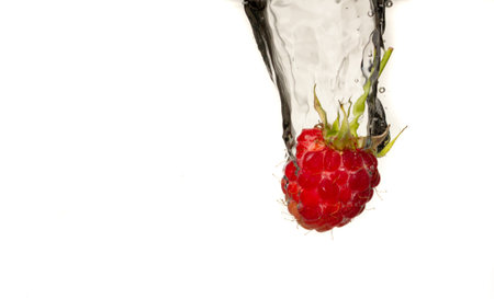 Close-up photo, on a very short exposure, strawberries falling into the water on a white background