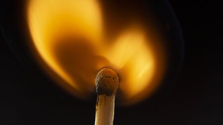 Burning wooden match with a red match head on a black background. Close upの写真素材