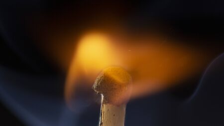 Burning wooden match with a red match head on a black background. Close upの写真素材