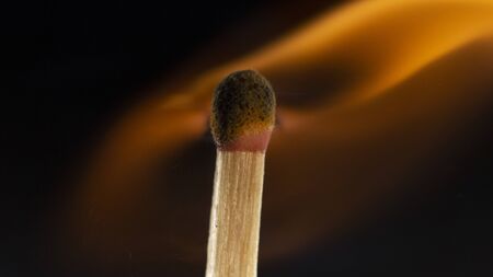 Burning wooden match with a red match head on a black background. Close upの写真素材