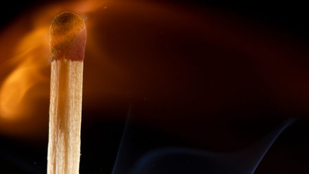 Burning wooden match with a red match head on a black background. Close upの写真素材
