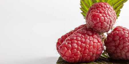 Group of three raspberries with leaves isolated on a white background close up
