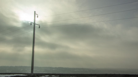 High voltage electricity transfer lines and pylon in a foggy morningの写真素材