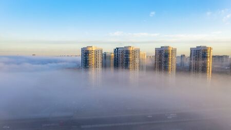 Autumn morning fog creeping into the city, the tops of high-rise buildings look like fog.の写真素材
