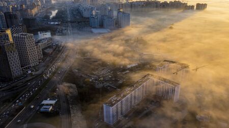 Autumn morning fog creeping into the city, the tops of high-rise buildings look like fog.の写真素材