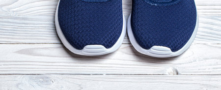 ancestors of blue high quality running shoes on white wooden background closeup.