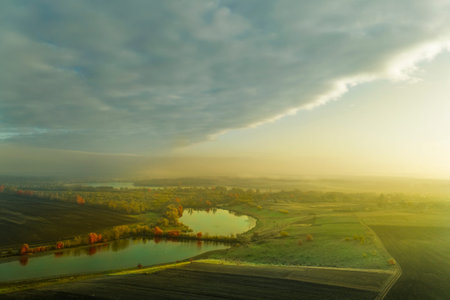 Fog is approaching the autumn meadow with the lake.