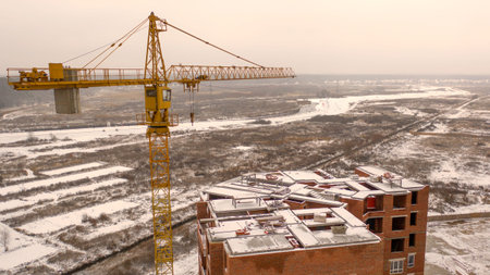 Construction site covered with snow. Multi-storey house under construction in the city. View from the droneの写真素材