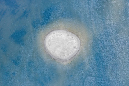 A small empty island in the middle of a frozen lake, winter landscape. Minimalism.