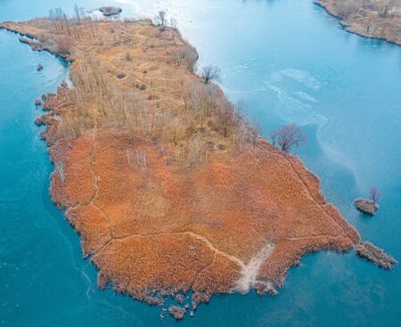 A small island in the center of a frozen lake. Autumn landscape.の写真素材