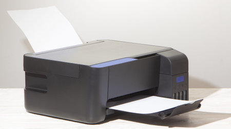 Black printer with scanner, on white wooden table.