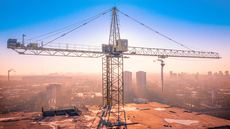 Multi-storey building, tower crane and construction site, top view. At sunset.